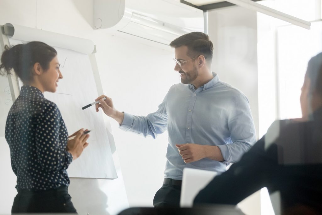 Diverse speakers make flip chart presentation in conference room