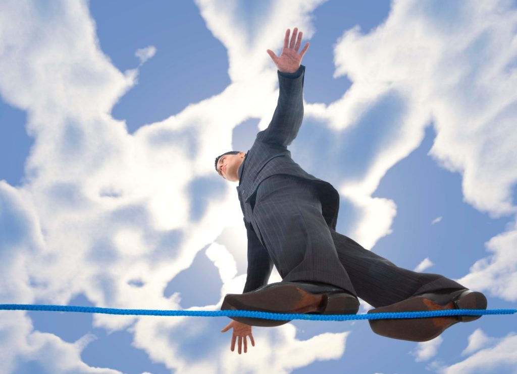 Young businessman walking on line in the air. Holding balance. Low angle view