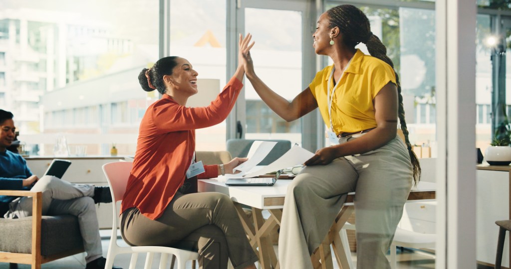 Paperwork, business women and high five for goal achievement, success and target in office. Happy team, startup and celebration for milestone, support or good news with document in creative company.